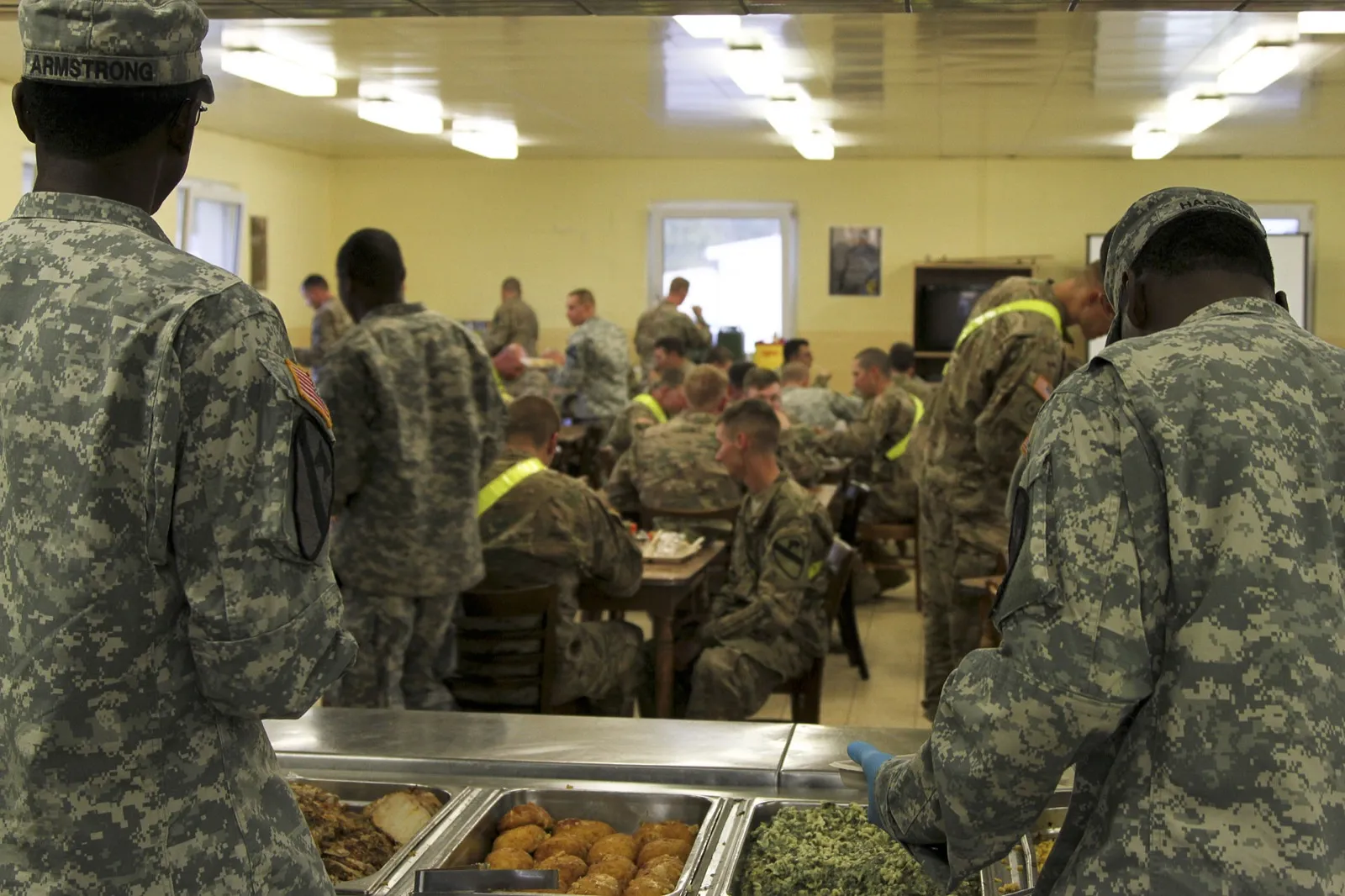 Soldiers being served hot food in a base dining facility