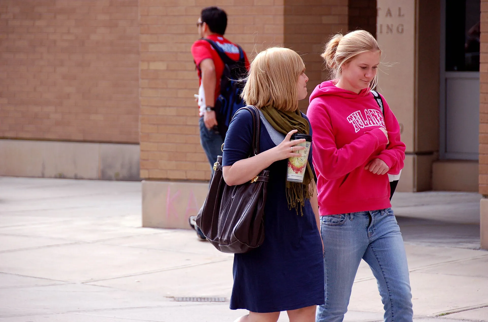 A student veteran walking across a college campus with a backpack, the kind of GI Bill student who receives a monthly housing allowance