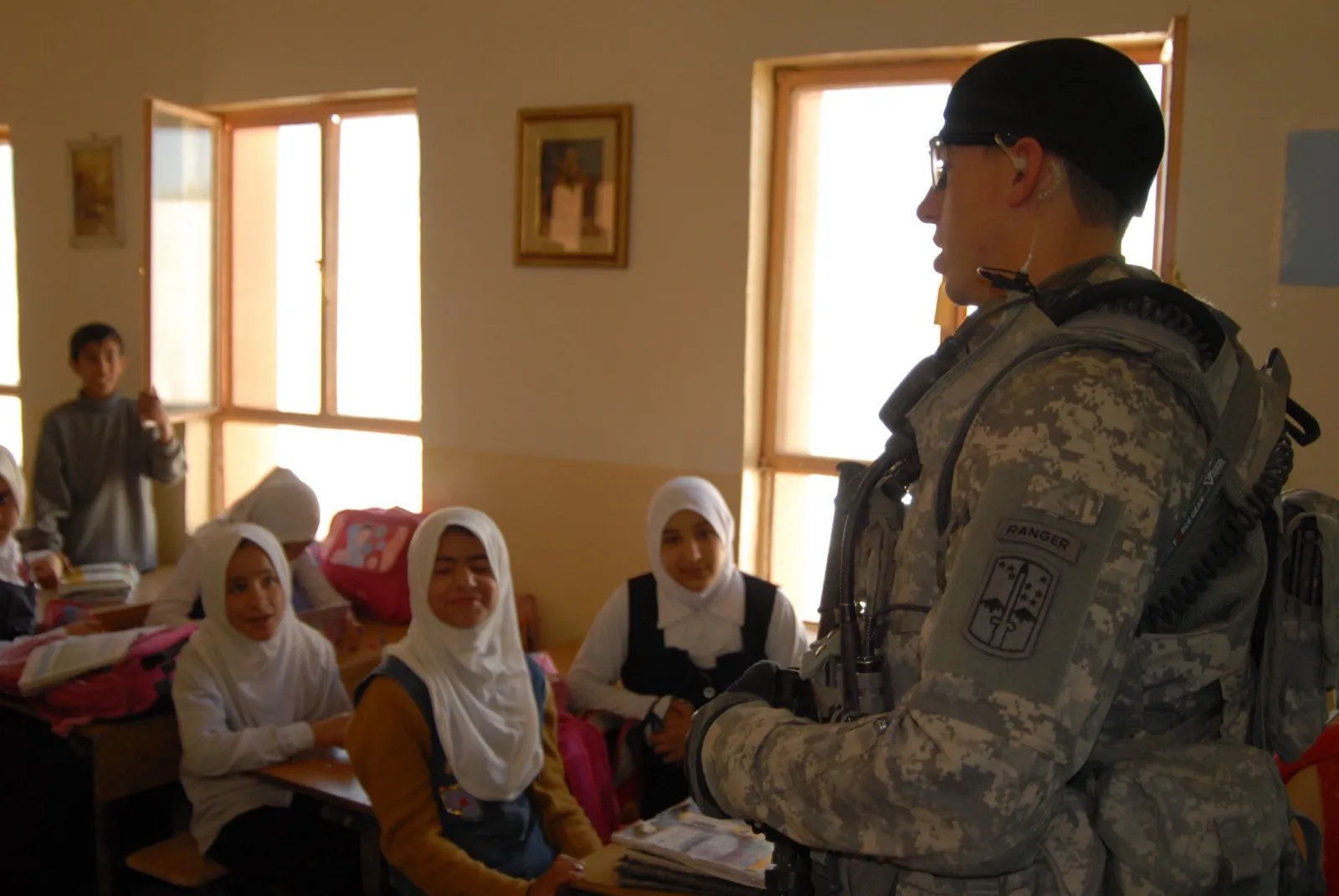 Service members and veterans sit at desks in a college classroom taking notes during a lecture