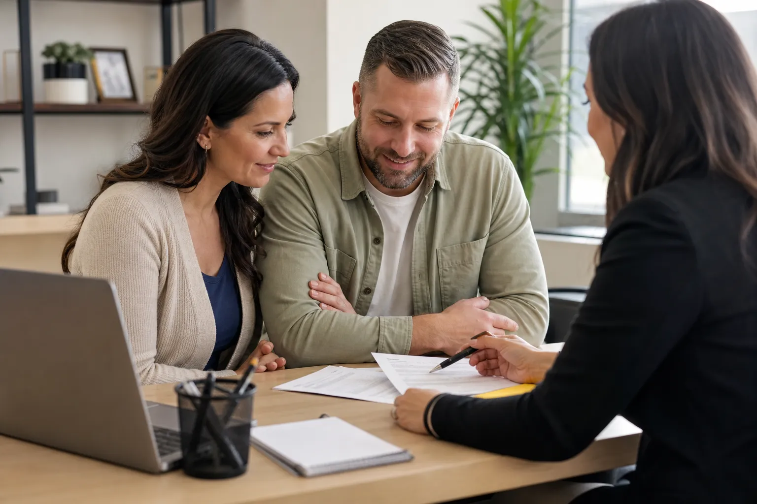A veteran couple sitting at a lender's desk reviewing VA home loan paperwork
